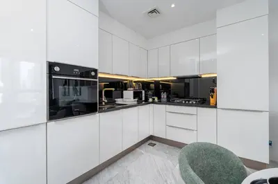 a kitchen with white cabinets and a green chair at Cosmopolitan Apartment with Burj Khalifa View in Dubai