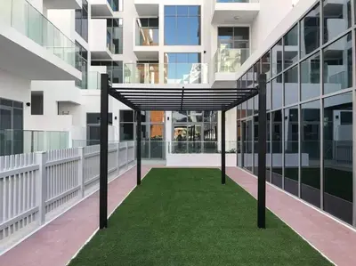 a building with a green lawn in the middle of a building at Cozy studio in heart of Dubai - JVC in Dubai