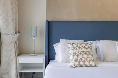 a bed with a blue headboard and a pillow and a lamp at Daniels 1BR Business Bay Partial Burj Khalifa View in Dubai