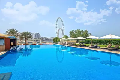 a large swimming pool with a ferris wheel in the background at Al Bateen · Ultra Luxury JBR · Private Beach and Pool in Dubai