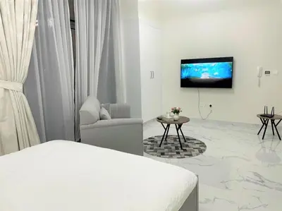 a white room with a bed and a tv on a wall at Amazing stay in Majan Dubai in Dubai
