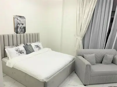 a white bedroom with a bed and a chair at Amazing stay in Majan Dubai in Dubai