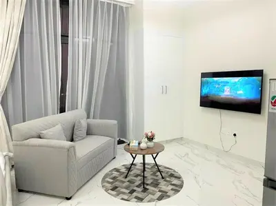 a living room with a couch and a tv on a wall at Amazing stay in Majan Dubai in Dubai