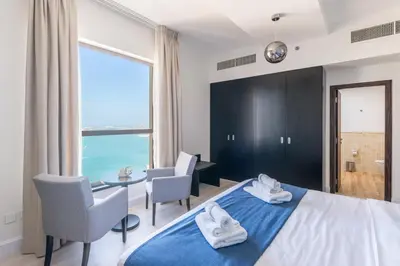 a bedroom with a bed and a table and chairs at Luxury JBR Shams - Marina View - Free 5 star Beach Resorts Access! in Dubai