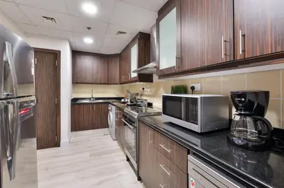 a kitchen with wooden cabinets and stainless steel appliances at Luxury JBR Shams - Marina View - Free 5 star Beach Resorts Access! in Dubai