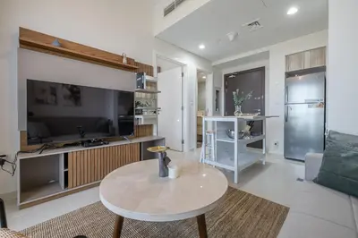 a living room with a table and a kitchen at City View I 1 Bedroom Apartment I Golf Vita, Damac Hills in Dubai