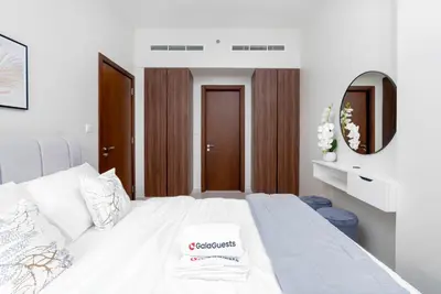 a bedroom with a white bed and a mirror at Gala Guests - Marasi Drive City View Apartments in Dubai