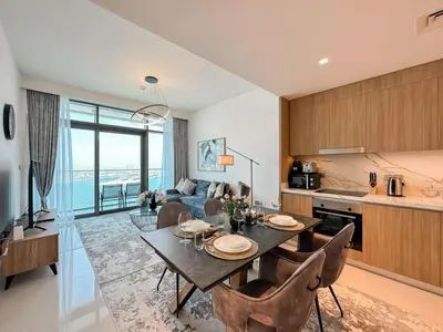a kitchen and living room with a table and chairs at Beachfront 2BR with Spectacular Sea and Palm Views - 17AB06 in Dubai