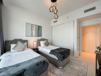 a bedroom with two beds and a chandelier at Beachfront 2BR with Spectacular Sea and Palm Views - 17AB06 in Dubai