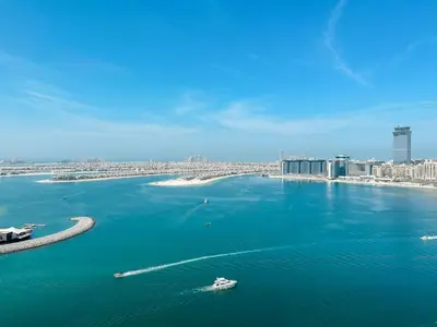 a boat in the water with a city in the background at Beachfront 2BR with Spectacular Sea and Palm Views - 17AB06 in Dubai