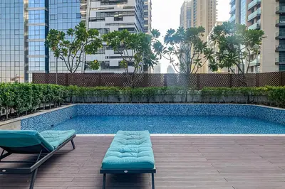a swimming pool with two chaises next to a building at Frank Porter - RP Heights in Dubai