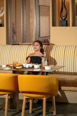 a woman sitting at a table in a restaurant at Cheval Maison - The Palm in Dubai