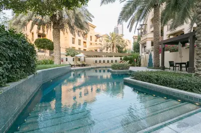 a swimming pool in a courtyard with palm trees at Old Town- Heart of Downtown. in Dubai