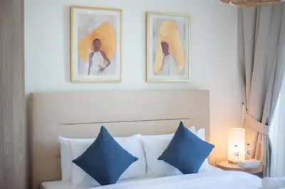 a bedroom with a bed with blue pillows and paintings on the wall at Beautiful, Stylish and Peaceful 1BD in JVC in Dubai