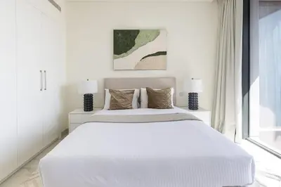 a white bedroom with a large bed and a window at Frank Porter - One Park Avenue in Dubai