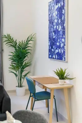 a table and chairs in a living room with a painting at Brand New 1BR in Dubai Hills Quiet and Peaceful in Dubai