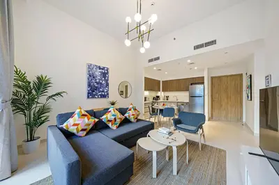 a living room with a blue couch and a table at Brand New 1BR in Dubai Hills Quiet and Peaceful in Dubai