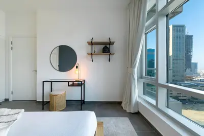 a bedroom with a bed and a mirror and a window at Maison Privee - Balinese Style Apt in the Heart of Downtown Dubai in Dubai