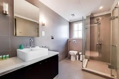 a bathroom with a sink and a shower and a toilet at Whispering Pines, JGE - Exquisite Three Bedroom Villa in Dubai