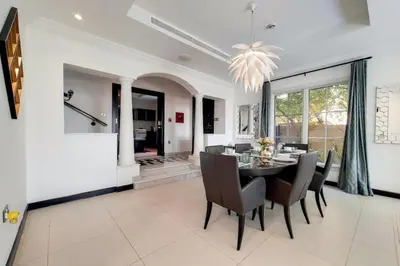 a dining room with a table and chairs at Whispering Pines, JGE - Exquisite Three Bedroom Villa in Dubai