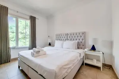 a white bedroom with a large bed and a window at Whispering Pines, JGE - Exquisite Three Bedroom Villa in Dubai