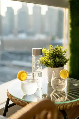 a glass table with a bottle of water and lemon slices at Luxury Apt - Rooftop Pool - City View in Dubai