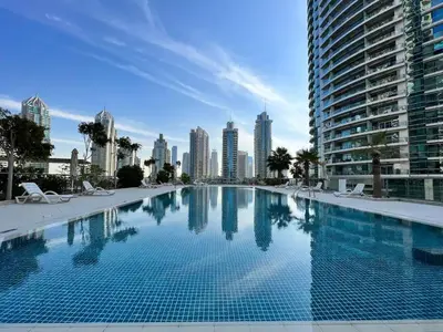 a large swimming pool with a city skyline in the background at Vacay Lettings - Iris blue spectacular Marina view Apartment in Dubai