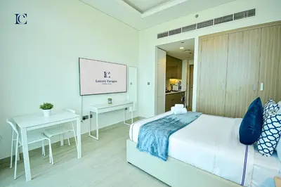 a bedroom with a bed and a table and a screen at Luxury Escapes - Brand New Studio with View - Azizi Farhad Jaddaf in Dubai