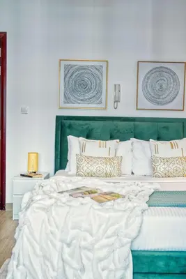 a bedroom with a large bed with a green headboard at The Smart Concierge - DEC Tower in Dubai