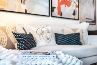a living room with pillows and a table with a book at The Smart Concierge - Sparkle tower in Dubai