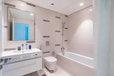 a white bathroom with a tub and a toilet and a sink at The Smart Concierge - Beach Vista Tower in Dubai