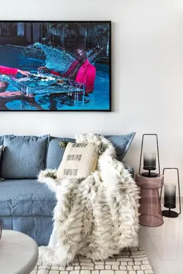 a living room with a blue couch with a picture on the wall at The Smart Concierge - Beach Vista Tower in Dubai
