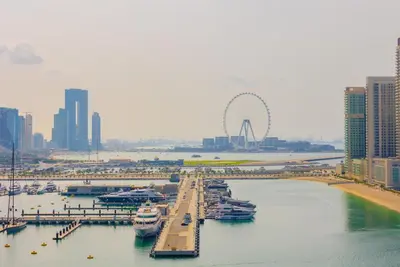 a group of boats docked at a marina with a ferris wheel at EDEN'S Homes & Villas - FIVE Palm Residences Penthouses in Dubai