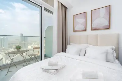 a bedroom with a white bed and a large window at Nice Studio in JVC - Pool & Gym in Dubai
