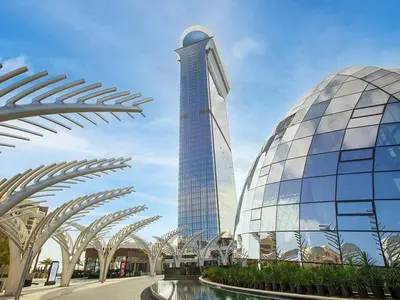 a large glass building with a tower in the background at Studio Apartment in The Palm Tower 5 Star Facilities in Dubai