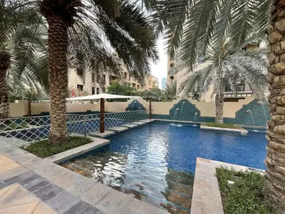 a swimming pool with palm trees in a resort at GuestReady - Luxe Arabian Apartment in Downtown in Dubai