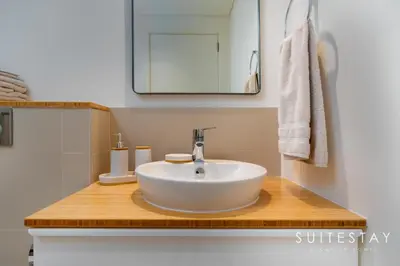 a bathroom with a white sink on a wooden counter at Chic One Bedroom Suite with Cozy Interiors in Dubai