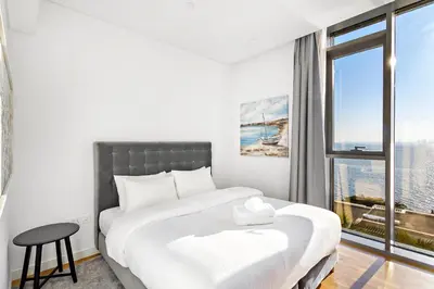 a white bedroom with a large bed and a window at Phenomenal 2BR with Scenic Sea-View from ALL rooms! in Dubai