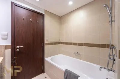a bathroom with a bath tub and a wooden door at Marco Polo - Wake up to breathtaking Burj Khalifa views in Dubai