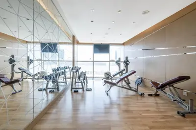 a gym with several treadmills and cardio machines at Tranquil 1BR apartment in Carson C, Damac Hills - Allsopp&Allsopp in Dubai
