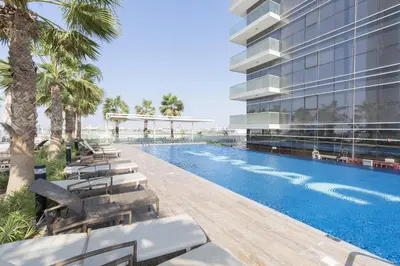 an exterior view of a building with a swimming pool at Tranquil 1BR apartment in Carson C, Damac Hills - Allsopp&Allsopp in Dubai