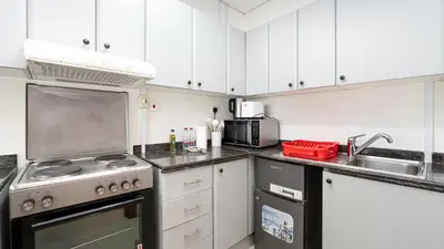 a kitchen with white cabinets and a stove top oven at Cosy 1 Bedroom Marina Apartment in Dubai