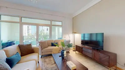 a living room with a couch and a tv at Elegant 2 BR Apartment with Beach Access in Dubai