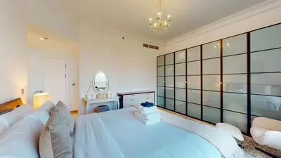 a bedroom with a large white bed and a mirror at Elegant 2 BR Apartment with Beach Access in Dubai