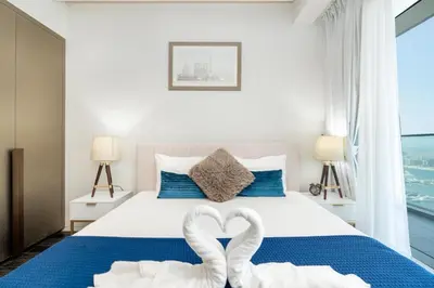 two swans shaped towels on a bed in a bedroom at White Sage - Fendi Apartment With Full Palm Jumeirah View in Dubai