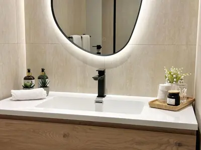 a bathroom sink with a round mirror above it at Family apartment next to the beach in Dubai