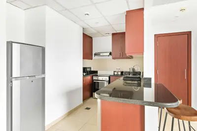 a kitchen with red cabinets and a stainless steel refrigerator at Silkhaus just furnished 1BDR in JBR near the beach in Dubai