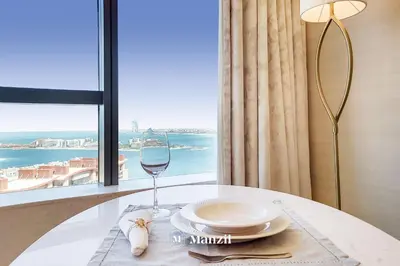 a glass of wine sitting on a table with a window at Manzil - Studio Apartment with Aura Pool & Sea View at The Palm Tower in Palm Jumeirah in Dubai