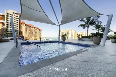 a swimming pool with an umbrella and the ocean at Manzil - Studio Apartment with Aura Pool & Sea View at The Palm Tower in Palm Jumeirah in Dubai