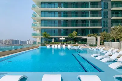 a swimming pool with white chairs and a building at Frank Porter - Beach Vista Tower 2 in Dubai